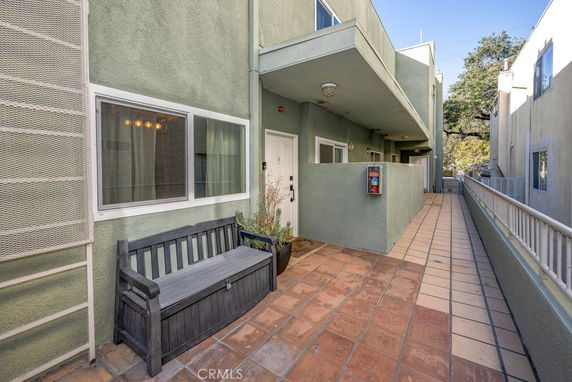 Exterior view of an apartment building with green walls, a bench, and walkway.