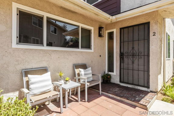 Front view of a house entrance with two chairs and a small table outside.