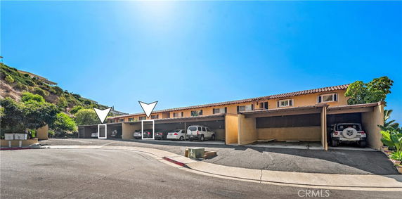 Outdoor parking area with covered parking spaces in front of a residential building.