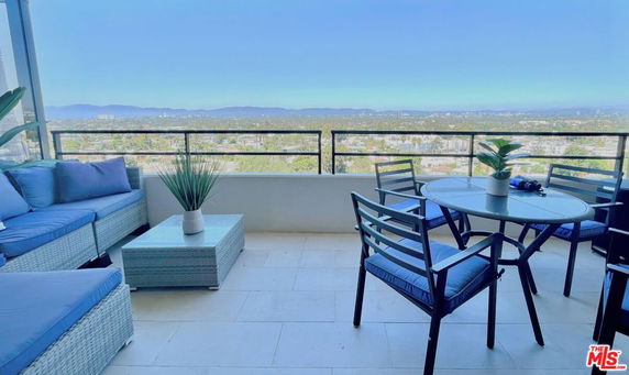 Outdoor seating area with panoramic view of cityscape and mountains.