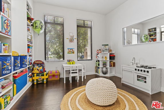 Children's playroom with toys, bookshelves, and a small play kitchen.