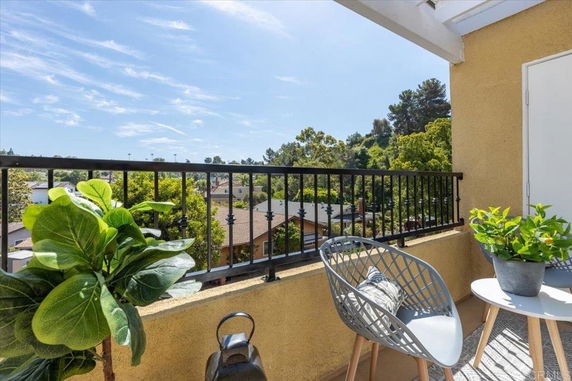 Elevated view from a balcony overlooking residential and tree-filled surroundings.