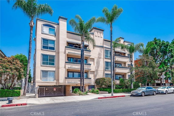 Front view of a multi-story apartment building with balconies and a gated entry.