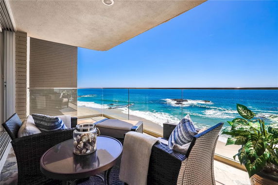 Outdoor seating area with ocean view from a balcony.