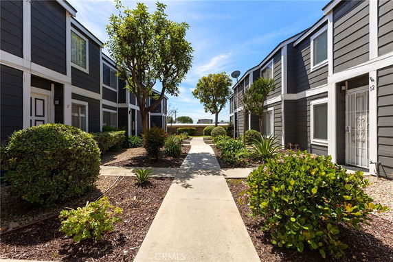 Front view of a row of two-story apartment buildings with a pathway and landscaped area.
