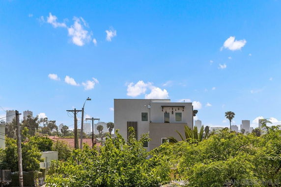 Distant view of a modern building with trees and cityscape in the background.