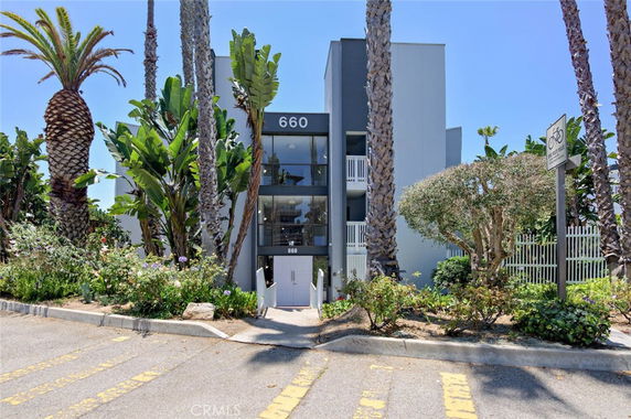 Front view of a multi-story building with palm trees and a visible entrance.