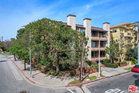 Front view of a multi-story residential building on a street corner.