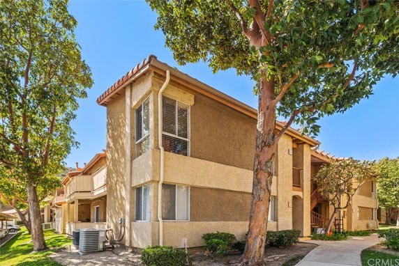 Front view of a two-story apartment building with beige stucco exterior and red tile roof.