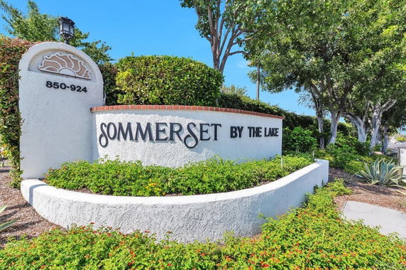 Entrance sign for 'Sommerset by the Lake' surrounded by greenery.