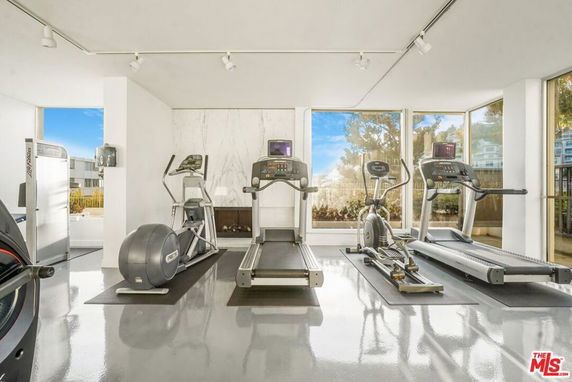 Indoor gym area with exercise equipment and large windows.