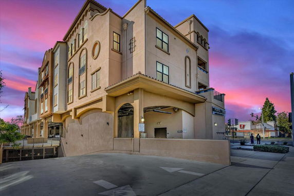 Front view of a multi-story building with an arched entrance and decorative architectural elements.