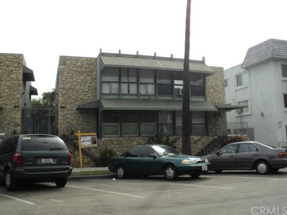 Front view of a stone-clad building with large windows and a small parking area.