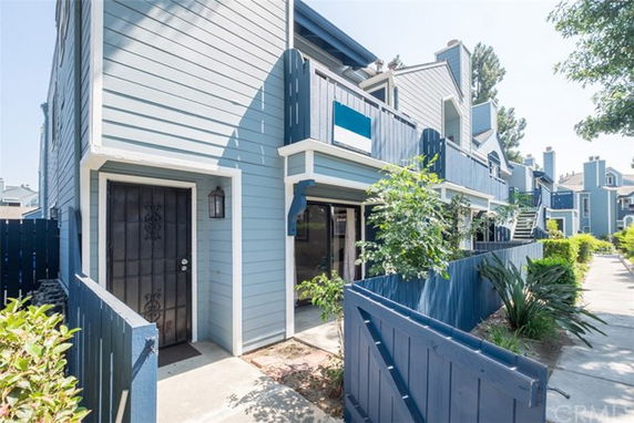 Front view of a two-story townhouse with blue siding and a small fenced front area.