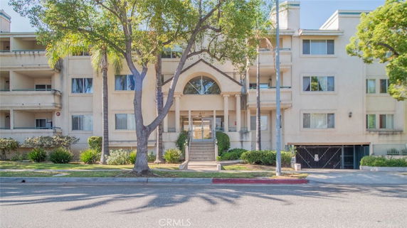 Front view of a multi-story residential building with balconies and arched entrance.