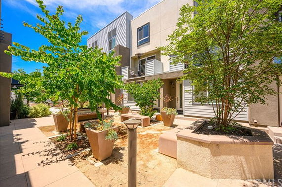 Front view of a modern multi-story building with balconies and potted plants.