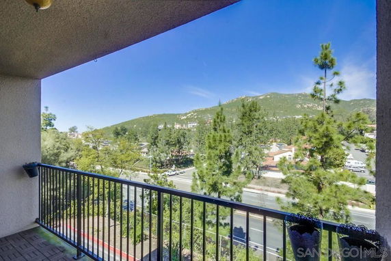 View from a balcony overlooking trees and mountainous landscape in the distance.