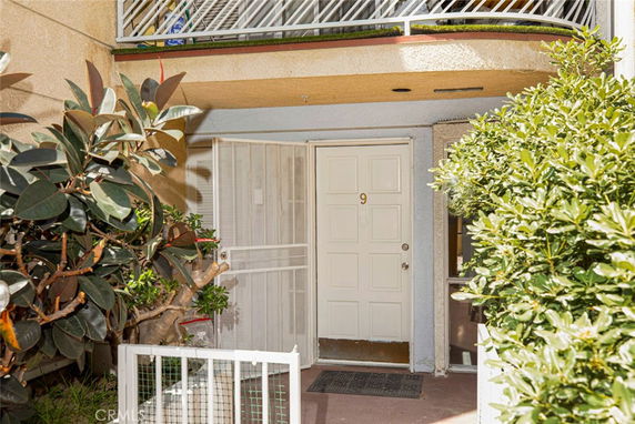 Front view of an apartment entrance with a white door and bushes on either side.