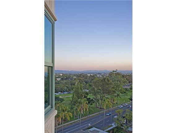 Panoramic view from a high-rise building window overlooking a cityscape with roads and greenery.