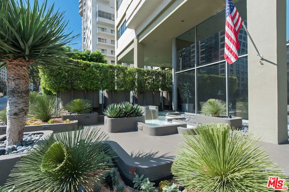 Front view of a modern building with large glass windows and landscaped garden.