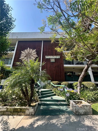 Front view of a mid-century style apartment building with wooden paneling and decorative sunburst design above the entrance.