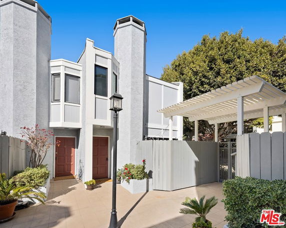 Front view of a two-story house with tall chimneys and gated entrance.