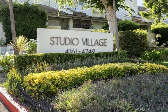 Front view of a building with a sign reading 'Studio Village 4161-4249' and surrounding greenery.