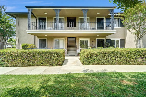 Front view of a two-story building with a central staircase and patio areas on both levels.