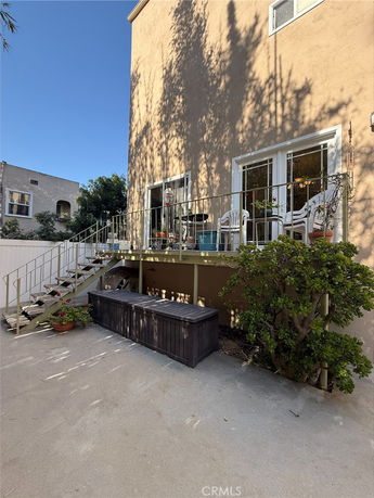 Side view of a multi-story house with a balcony and outdoor seating area.