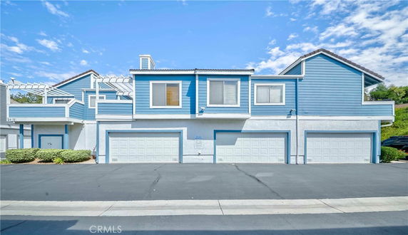 Front view of a multi-story house with blue and white exterior and multiple garages.
