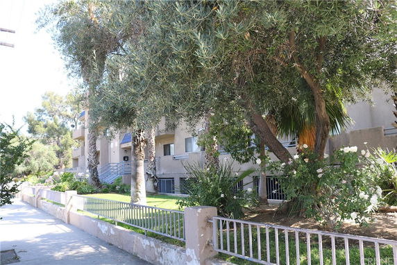 Front view of an apartment building with balconies and surrounding trees.