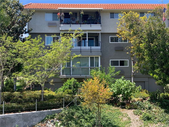Front view of a multi-story building with balconies and a red-tiled roof.