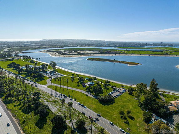 Aerial panoramic view of a large body of water surrounded by green landscapes and roads.