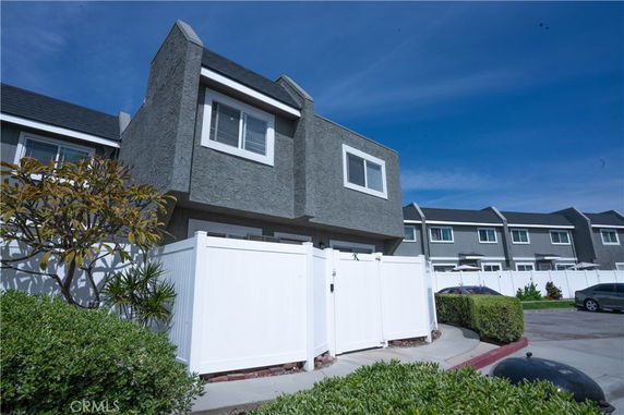 Front view of a two-story townhouse with a white fence.