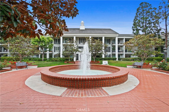 Front view of a multi-story building with balconies and a fountain.