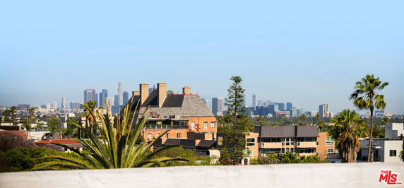 Panoramic view of a city skyline with buildings and palm trees visible.