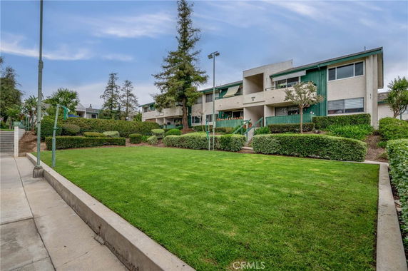Front view of a multi-story residential building with balconies and greenery.