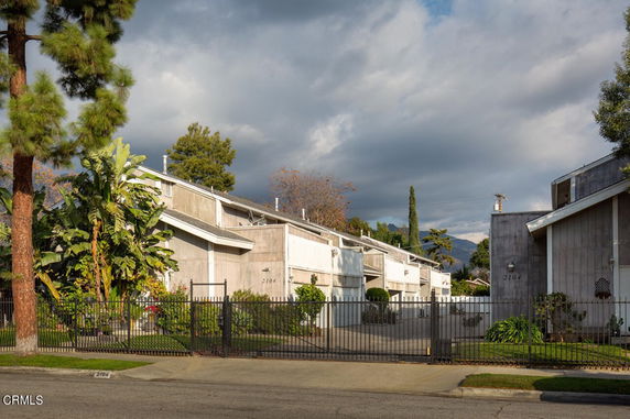 Front view of modern multi-story townhouses with gated entrance.