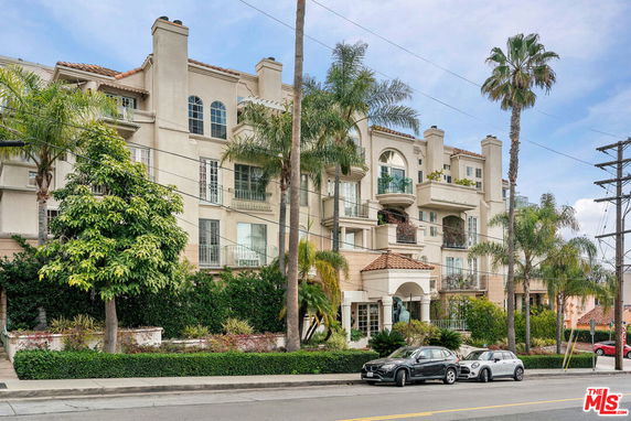 Front view of a multi-story building with balconies and an arched entrance.