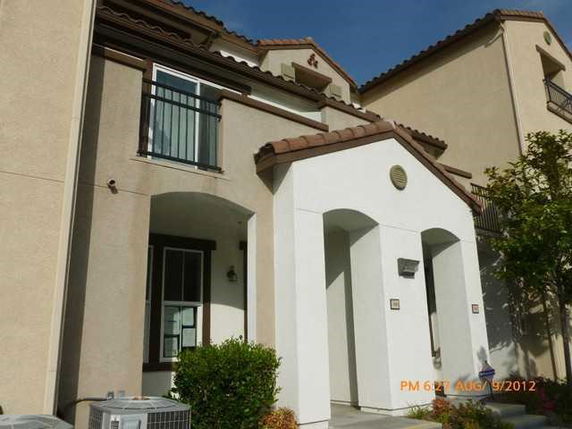 Front view of a multi-story house with arched entryway and balcony.