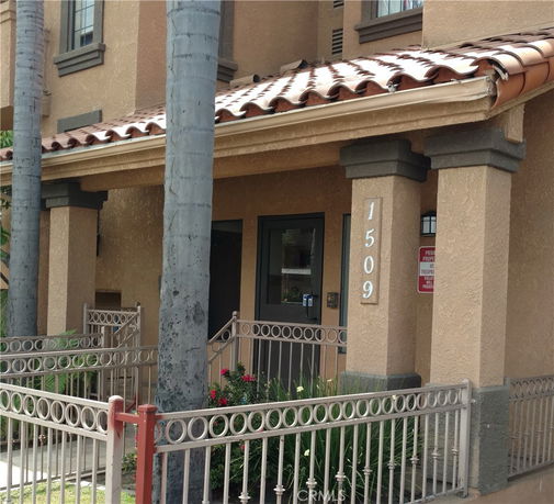 Front view of a building with a tiled roof and a fenced entrance.