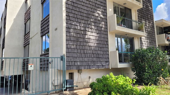 Front view of a multi-story building with balconies and shingle cladding.