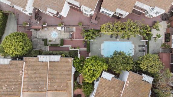 Aerial view of a residential complex with a central swimming pool surrounded by buildings.