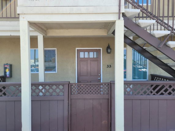 Front view of a house with stairs on the right side and a small fenced entrance.
