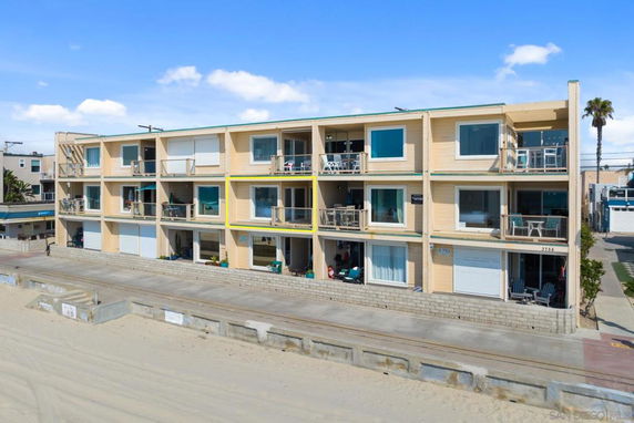 Front view of a three-story apartment building near the beach with balconies.