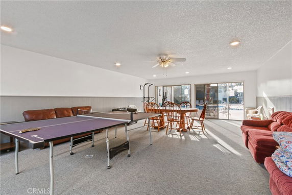 Interior view of a recreation room with a ping pong table, dining table, and sofas.