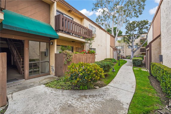 Pathway between residential buildings with wooden balconies and green awnings.