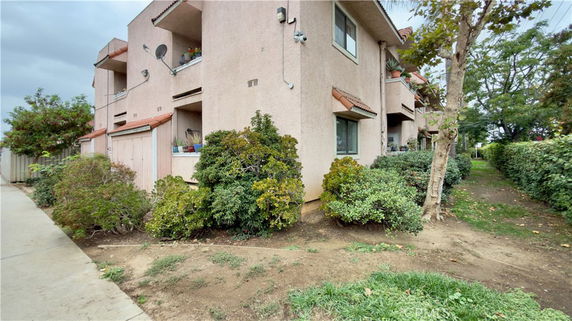 Corner view of a multi-story residential building with balconies and surrounding greenery.