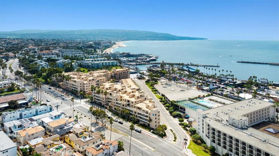 Aerial view of a coastal city with buildings and a marina by the sea.