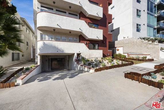 Front view of a multi-story residential building with balconies and a garage entrance.